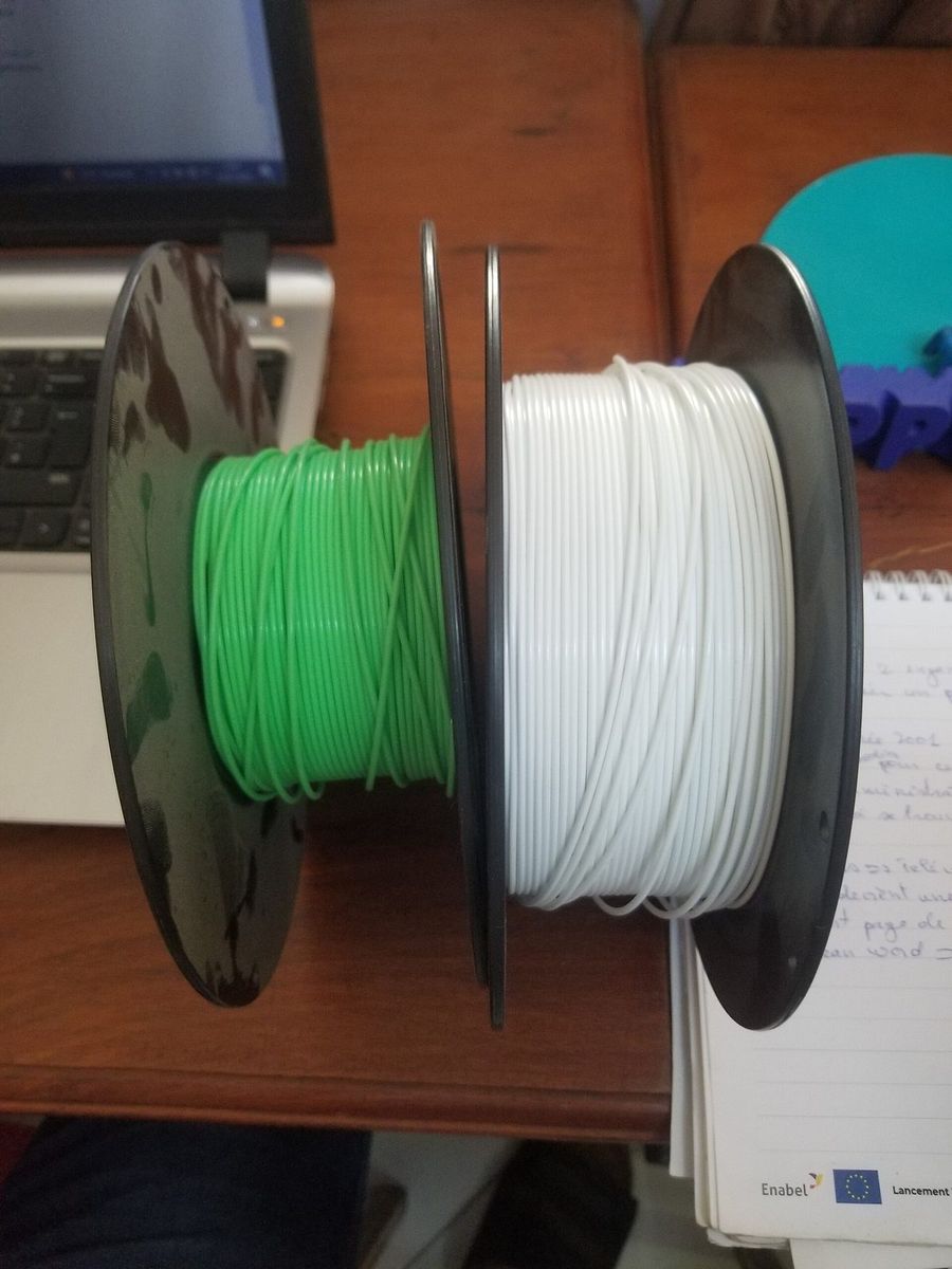 Carretéis de filamento PLA em várias cores empilhados, um deles aberto mostrando o filamento branco.